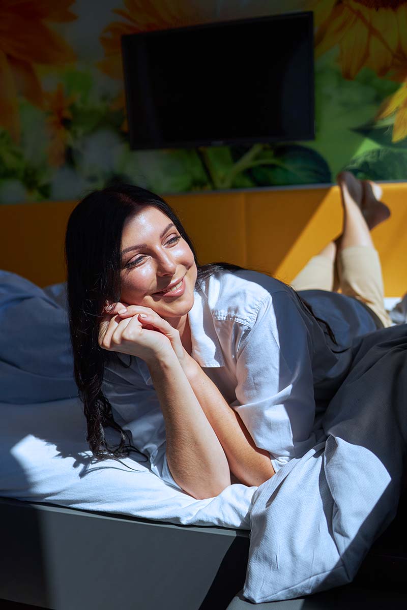 Frau liegt im Bett und lacht
